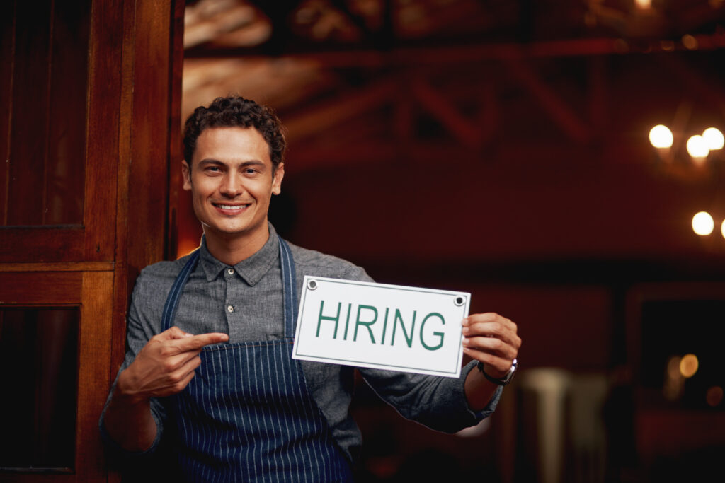 UK employer holding a “Hiring” sign, symbolising companies recruiting skilled workers in 2025.