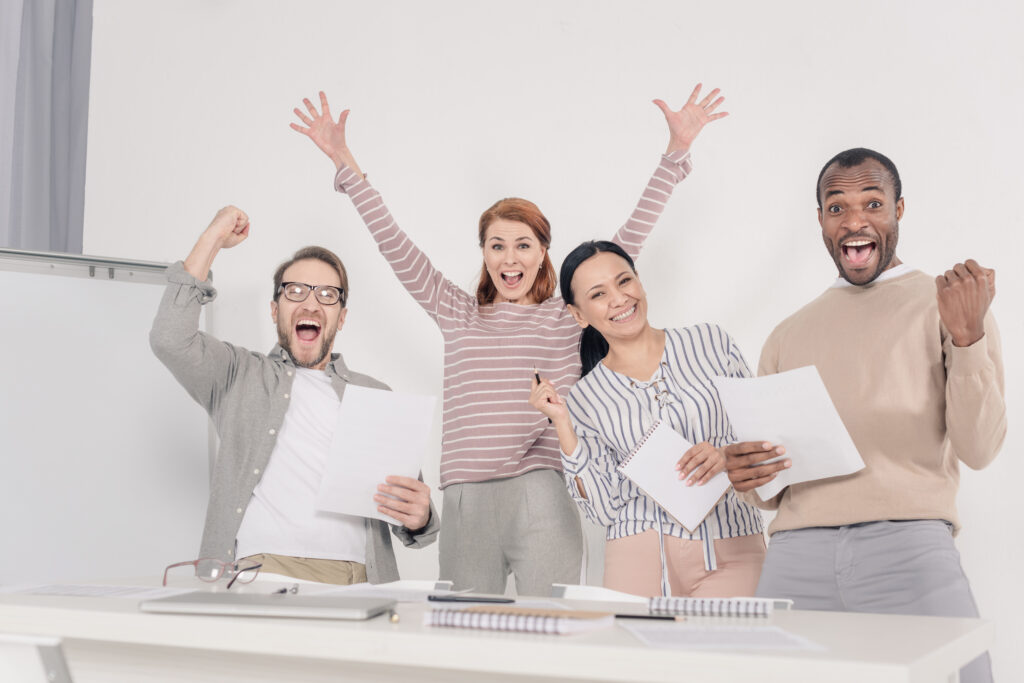 Excited diverse team of professionals celebrating successful UK sponsorship licence approval.