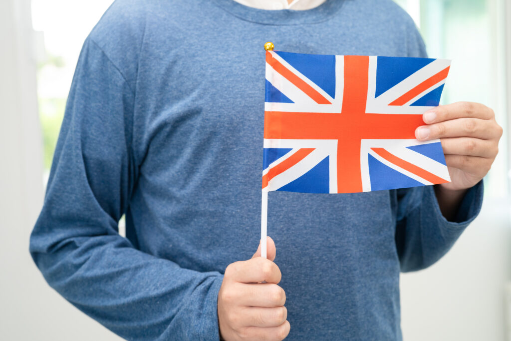A new arrival in the UK holding a small Union Jack flag, symbolising the start of their journey and integration during the first 90 days in the country.