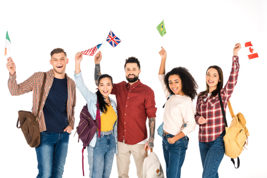 A diverse group of young professionals holding international flags and smiling, symbolising global talent seeking UK Skilled Worker visa opportunities.