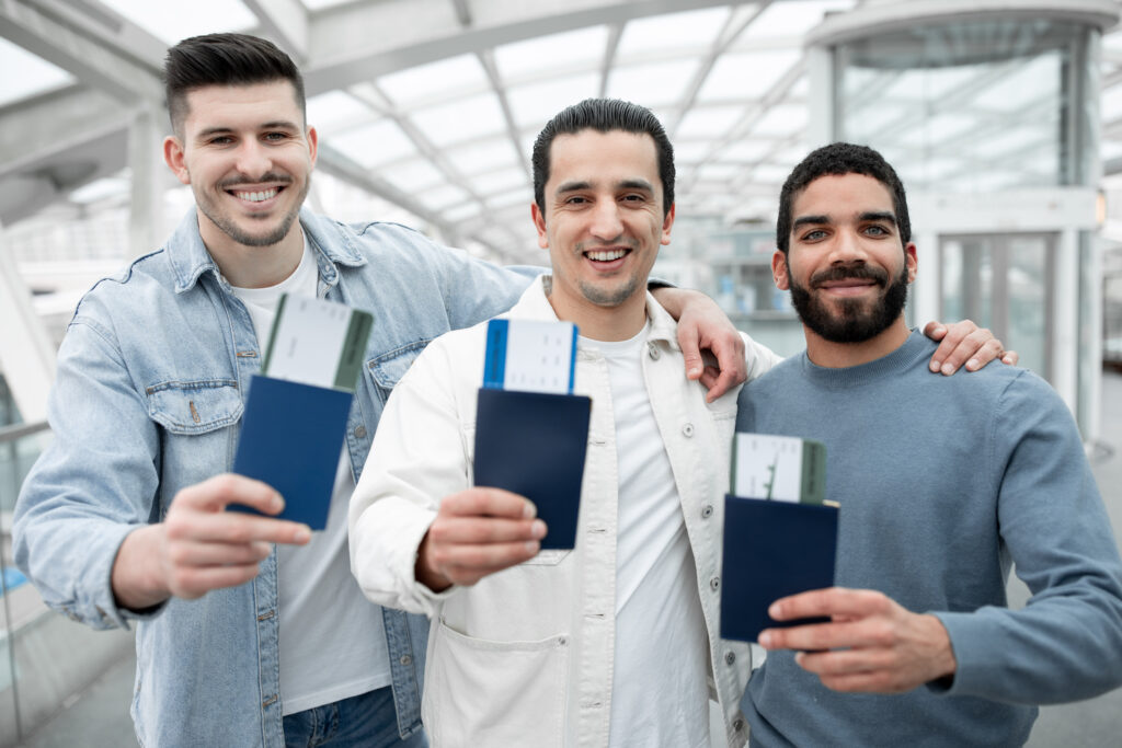 Three smiling skilled worker visa applicants holding passports and boarding passes at an airport.
