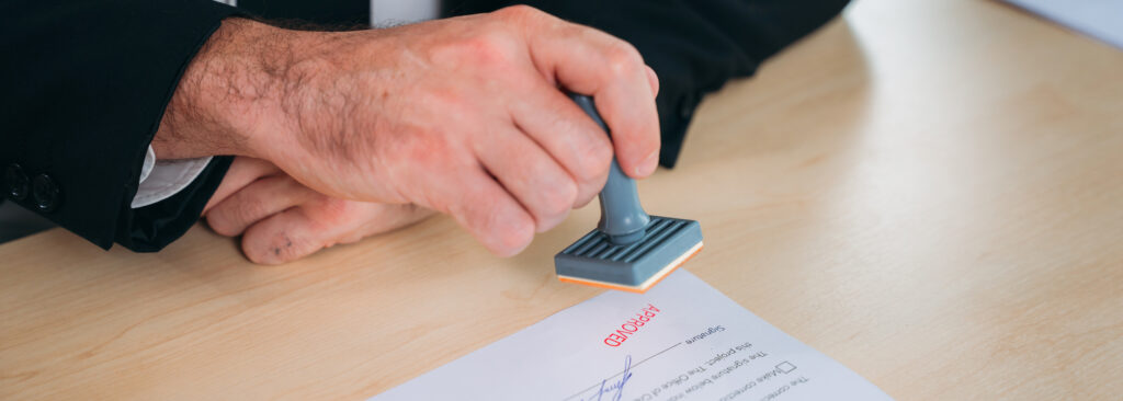 A UK Visas & Immigration officer reviewing a Skilled Worker visa application with official documents and criminal record certificates on a desk.