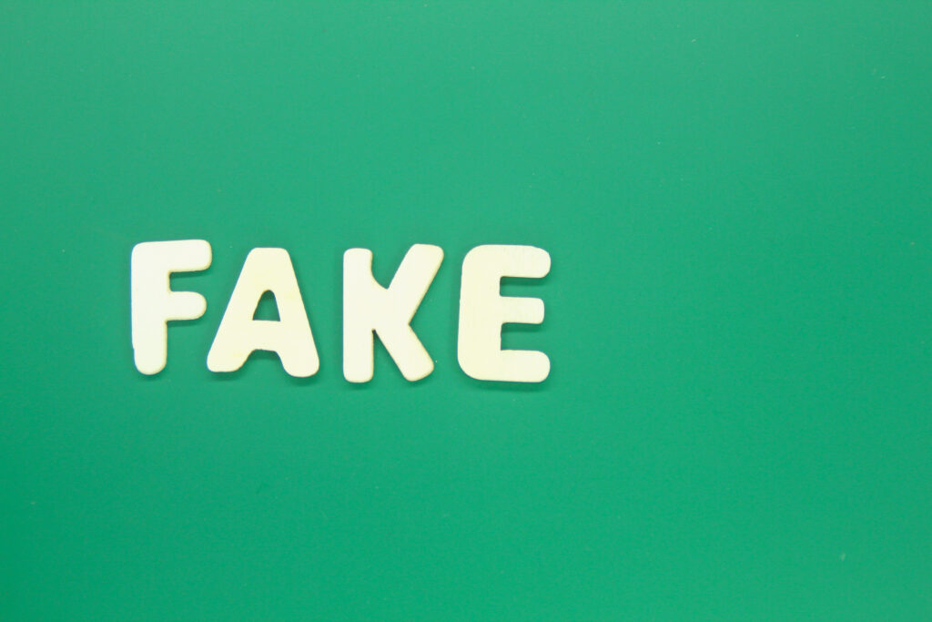 A person reviewing a UK job offer letter carefully under a magnifying glass, with a laptop displaying the GOV.UK visa portal in the background.