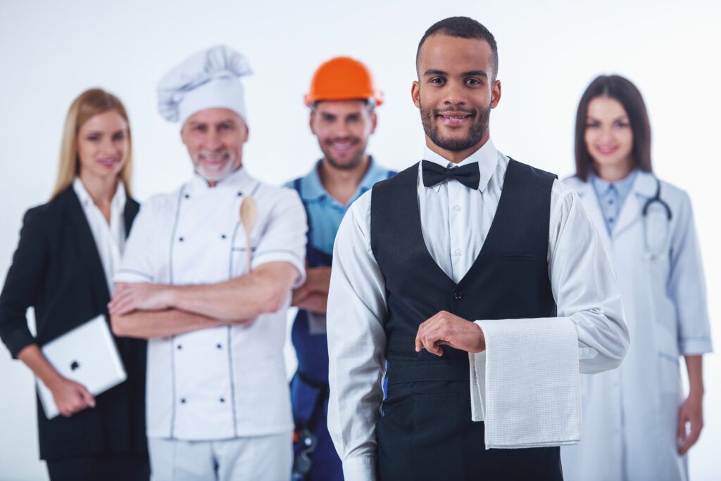 Hotel manager greeting staff in a modern UK hotel lobby, representing hospitality jobs open to Skilled Worker visa applicants in 2025.