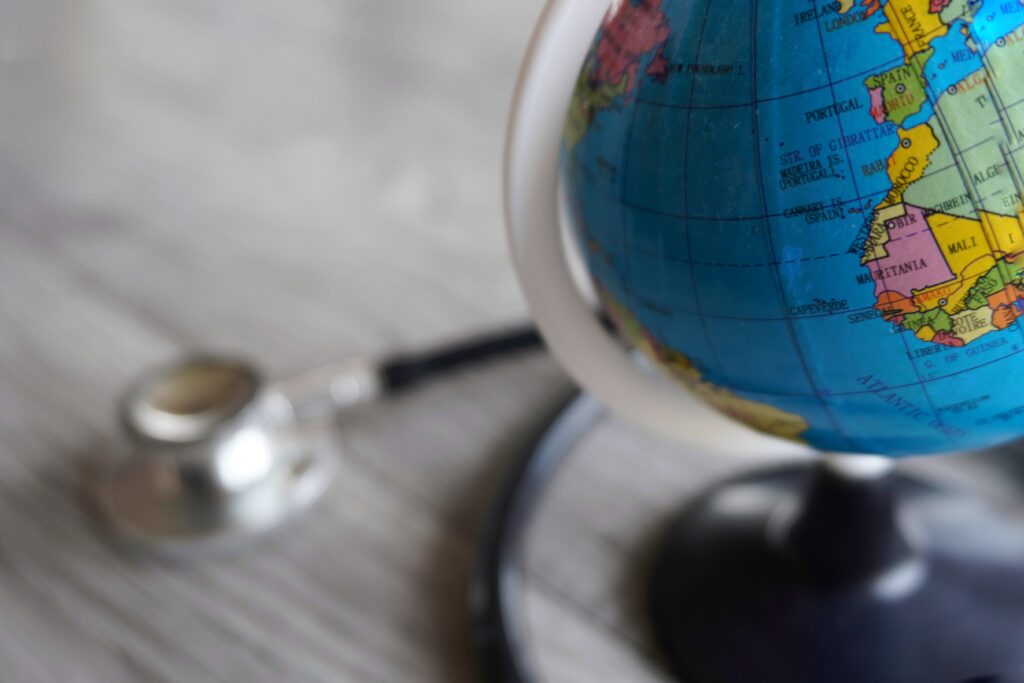 A Skilled Worker visa holder in the UK completing NHS GP registration paperwork at home, with a laptop, passport, and NHS documents on the table.
